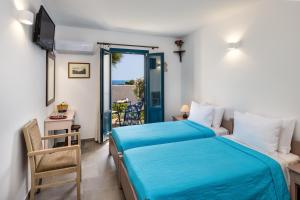 a bedroom with two beds and a balcony at Kalimera Hotel in Akrotiri