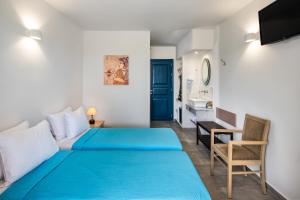 a bedroom with a blue bed and a desk at Kalimera Hotel in Akrotiri
