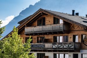 a log house with a balcony and mountains in the background at PUR Suites & Chalets in Lermoos