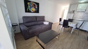 ein Wohnzimmer mit einem braunen Sofa und einem Tisch in der Unterkunft Apartamento Estudio Playmon Park 10-9 in Benidorm