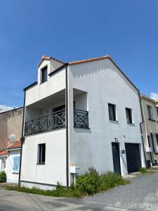 een wit gebouw met een balkon aan de zijkant bij Proche mer, plage et commerces à 500m in La Bernerie-en-Retz