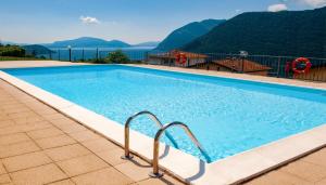 a large swimming pool with mountains in the background at Lake view 18 in Sale Marasino