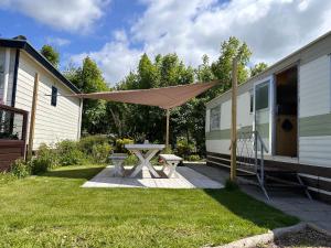 a picnic table with an umbrella next to a trailer at Retro Stacaravan in Warmond