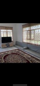a living room with a flat screen tv and two windows at Sun shine chalet in Al Ḩadd
