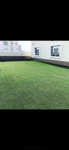 a large yard of green grass in front of a building at Sun shine chalet in Al Ḩadd