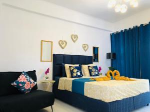 a bedroom with a bed with blue curtains and a chair at Urszula's apartment - apartments by the sea in Áyios Andréas Messinias