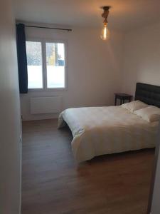 ein Schlafzimmer mit einem weißen Bett und einem Fenster in der Unterkunft Grand appartement, lumineux in Miniac-Morvan