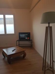 ein Wohnzimmer mit einem Couchtisch und einem TV in der Unterkunft Grand appartement, lumineux in Miniac-Morvan