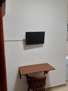 einen TV an einer weißen Wand mit einem Holztisch in der Unterkunft casa mariagrazia in La Caletta