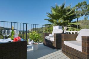 a balcony with wicker chairs and a table with wine glasses at Hotel Rural Can Maries in Puerto de San Miguel