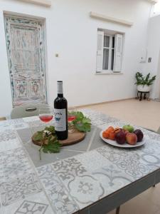 uma garrafa de vinho e um prato de fruta numa mesa em Kalymnos residence em Calímnos