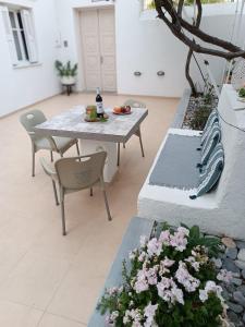 um pátio com uma mesa, cadeiras e flores em Kalymnos residence em Calímnos