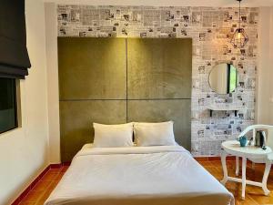 a bedroom with a bed with a large headboard and a table at Chernin hotel & Spa in Ban Bang Chak