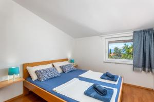 a bedroom with a bed with blue pillows and a window at Apartments Tamaris in Malinska