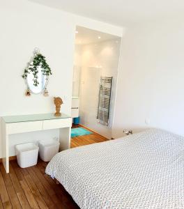 a white bedroom with a bed and a mirror at SUPERBE APPARTEMENT DANS CADRE D'EXCEPTION - Piscine, Plage et Tennis privé in Bandol
