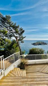 a wooden staircase leading to the ocean with a tree at SUPERBE APPARTEMENT DANS CADRE D'EXCEPTION - Piscine, Plage et Tennis privé in Bandol