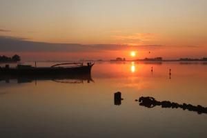 比丁赫茲的住宿－Houseboot Kingfisher, lake view，日落时分坐在水中的船