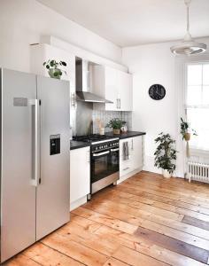 a kitchen with white appliances and a wooden floor at Luminous Town house by the sea in Kent