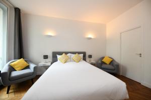 una camera da letto con un grande letto bianco e due sedie di Paris Square a Parigi