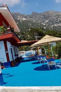 a pool with chairs and umbrellas next to a house at Ikaria Studios in Manganítis