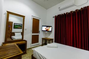 a room with two beds and a mirror and a television at Pearl Island Inn in Jaffna
