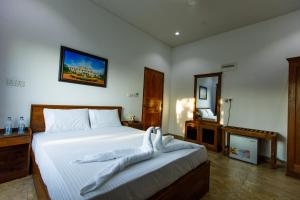 a bedroom with a bed with white sheets and a mirror at Pearl Island Inn in Jaffna