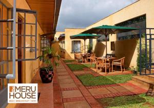een patio met tafels en parasols op een huis bij The Meru House in Nkubu