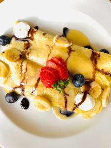 a white plate of food with bananas strawberries and blueberries at Drakensberg Inkosana Lodge in Champagne Valley