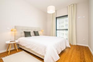 une chambre blanche avec un grand lit et une fenêtre dans l'établissement Apartment with ocean view and parking, à Funchal