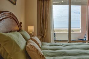 a bedroom with a bed with a view of the ocean at Varandas do Oásis in Figueira da Foz