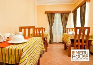 a hotel room with two beds and a table and chairs at The Meru House in Nkubu