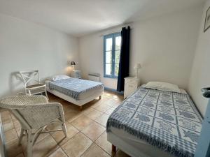 una camera con due letti e una sedia e una finestra di Maison Noirmoutier-en-l'Île, 4 pièces, 6 personnes - FR-1-224B-75 a Noirmoutier-en-l'lle
