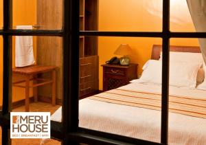 Schlafzimmer mit einem Bett und einem Fenster in der Unterkunft The Meru House in Nkubu