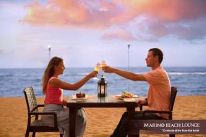 Ein Mann und eine Frau trinken Wein an einem Tisch am Strand. in der Unterkunft Marino Beach Colombo in Colombo