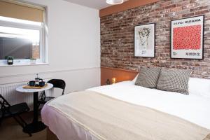 a bedroom with a brick wall and a bed and a table at Settle in Southampton in Southampton