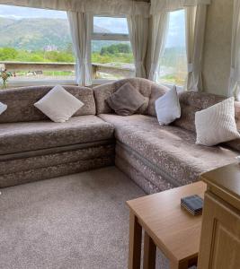 a living room with a couch with pillows and a table at Curacao Caravans in Taynuilt