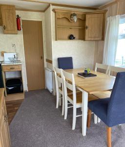 a kitchen and dining room with a wooden table and chairs at Curacao Caravans in Taynuilt