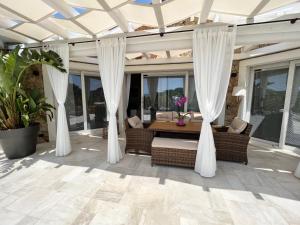 a screened porch with white curtains and a table at Suite Villa Aquamarina con Jacuzzi Riservata in Porto Pino