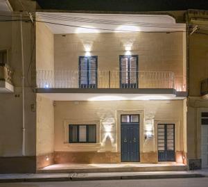 a building with a balcony and a blue door at Tal-Andar Farmhouse in Kerċem