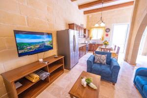 a living room with a flat screen tv on a wall at Tal-Andar Farmhouse in Kerċem