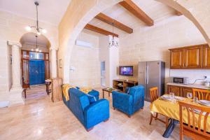 Kerċem的住宿－Tal-Andar Farmhouse，厨房以及带蓝色椅子和桌子的客厅。