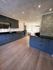 a large kitchen with blue cabinets and wooden floors at Östavall Kölsillre Lyxvilla, fiber internet WiFi in Haverö