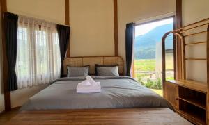 a bedroom with a bed with a large window at Times Klang Sapan Resort in Ban Sapan