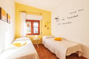 twee bedden in een kamer met gele muren bij Casa Sui Tetti in Baunei