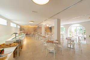 un restaurante con mesas y sillas blancas y ventanas en Hotel Internacional, en Benidorm