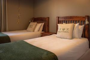 a hotel room with two beds with pillows at Beach Club Self Catering Apartments in Mossel Bay +65 photos