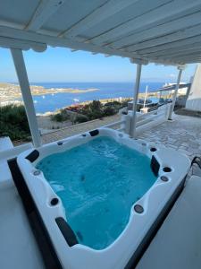 a hot tub on a patio with the ocean in the background at Villa Ocean prince in Mikonos