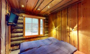 a bedroom in a log cabin with a bed and a tv at Holiday Apartments Aurinkosuomu in Kemijärvi