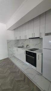 a kitchen with white cabinets and a black appliance at Flat in Trpejca in Ohrid +14 photos