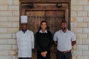 tres hombres y una mujer parados frente a una puerta en Inkungu Lodge, en Champagne Valley